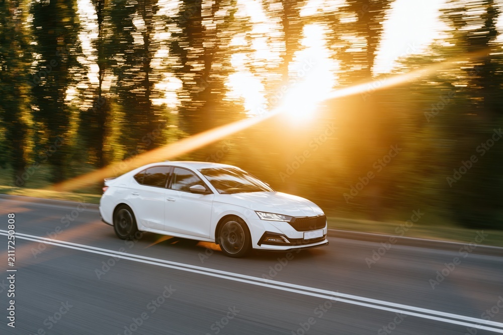 Naklejka premium The White Sedan on a Sunlit Highway During the Golden Hour