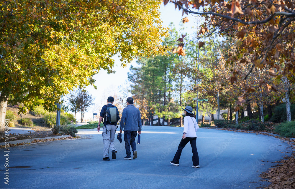 Fototapeta premium Three people walking across the road in autumn. Walkable city in California. USA.