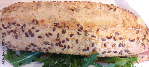 Serrano ham, cheese and arugula sandwich on seeded bread.