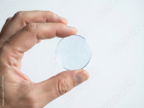 Hand holding clear lens optical glass component precision manufacturing
