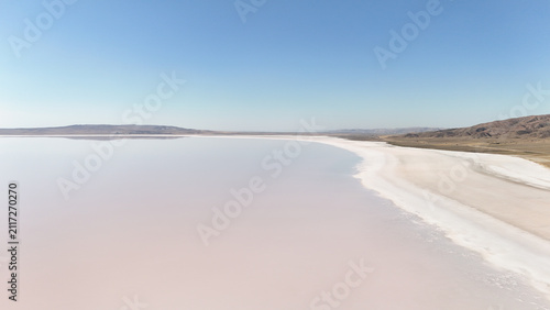 Aerial View of a Surreal Pink Salt Lake Under a Clear Blue Sky
