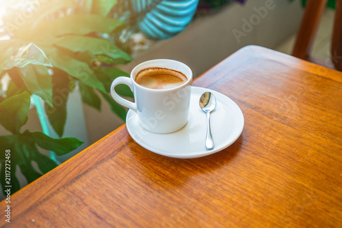 Cuadro en lienzo Hot americano coffee cup with golden crema on wooden table in garden cafe