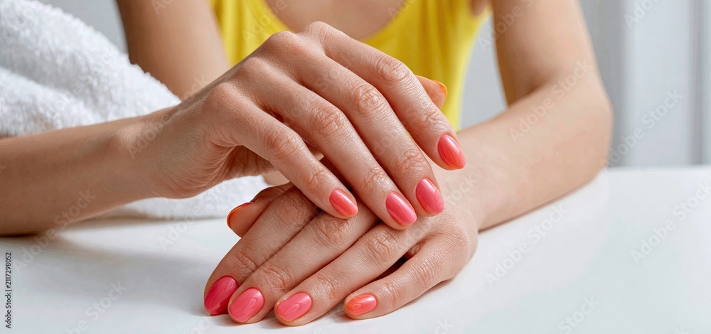 Fototapeta premium Hands with colorful nails getting shaped on a white surface in a bright, inviting beauty salon setting.