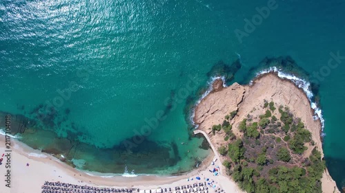 Beautiful aerial view of a sandy beach with crystal clear sea, turquoise water and visitors enjoying swimming and paddleboarding on Thassos Island, Greece.