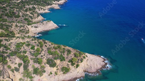 Aerial drone of a peaceful beach in Thassos, Greece, featuring transparent turquoise water, paddleboards, swimmers and a beautiful Mediterranean coastline.