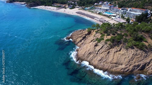Aerial drone  of a peaceful beach in Thassos, Greece, featuring transparent turquoise water, paddleboards, swimmers and a beautiful Mediterranean coastline.