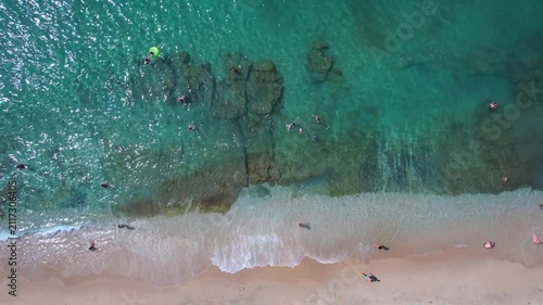 Beautiful aerial view of a sandy beach with crystal clear sea, turquoise water and visitors enjoying swimming and paddleboarding on Thassos Island, Greece.