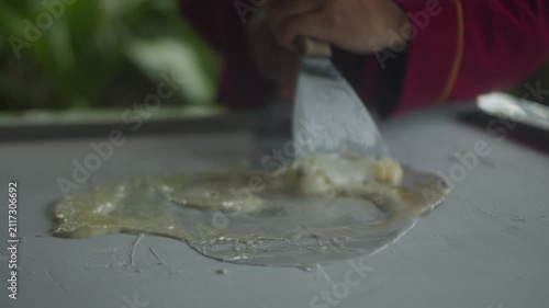 Close up of chef spreading mango ice cream on a frozen pan and carefully rolling it into neat ice cream rolls. Fresh homemade frozen dessert prepared by hand.