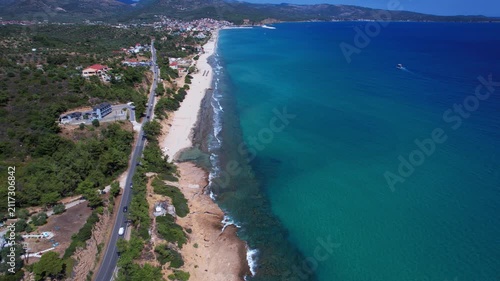 Aerial drone of a peaceful beach in Thassos, Greece, featuring transparent turquoise water, paddleboards, swimmers and a beautiful Mediterranean coastline.