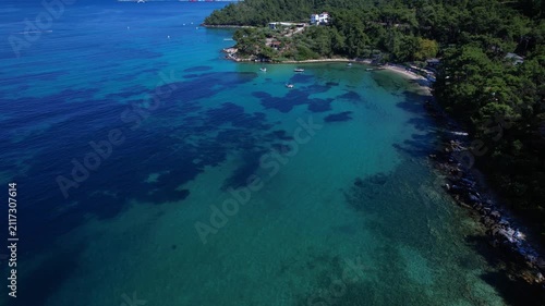 Beautiful aerial view of a sandy beach with crystal clear sea, turquoise water and visitors enjoying swimming and paddleboarding on Thassos Island, Greece.