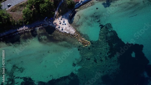 Aerial drone  of a peaceful beach in Thassos, Greece, featuring transparent turquoise water, paddleboards, swimmers and a beautiful Mediterranean coastline.