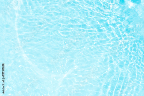 Blue water with ripples on the surface. Defocus blurred transparent white colored clear calm water surface texture with splashes and bubbles. Water waves with shining pattern texture background.