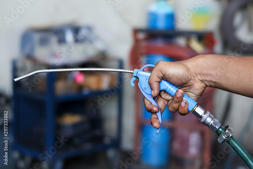 фотографія Worker holding a pneumatic air blow gun for cleaning machinery and parts in a workshop