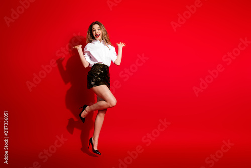 Quadro su tela Elegant young woman in stylish formalwear posing playfully against a vibrant red
