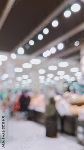 A blurred supermarket interior, glowing bokeh ceiling lights, and shoppers in motion.