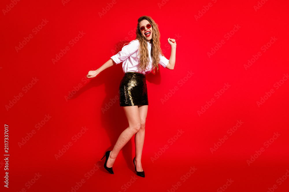 Obraz premium Joyful woman in stylish attire exudes charm and fun with dynamic pose on a vibrant red background