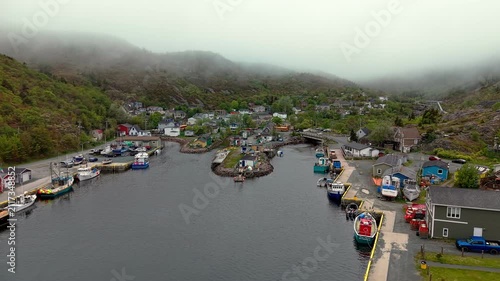 Aerial drone view of thick sea fog rolling over Petty Harbour fishing village in Newfoundland Canada