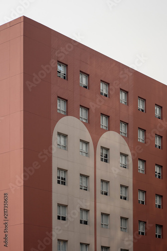 Modern red building facade with geometric white arch patterns and windows.