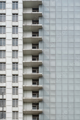Modern highrise building facade with contrasting white balconies and grey glass panels.