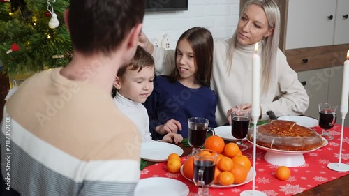 Happy family embracing at Christmas dinner table, loving parents with kids hugging during festive holiday meal, cozy winter evening celebration, family values and domestic lifestyle concept. Vigilia