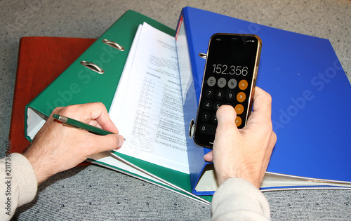 Konstfotografi Contable con calculadora móvil, sumar app teléfono y apuntar en papel resultado