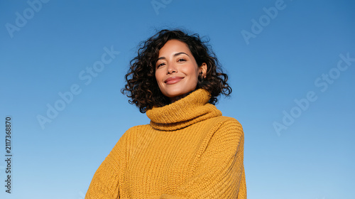 Young woman smiling in a yellow sweater against the blue sky  