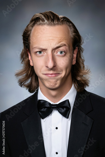 people of ai, yearbook photography of a person with slicked-back brown mullet, smug puckered lips, wearing black tuxedo, 1980s portrait blue, photorealistic DOC