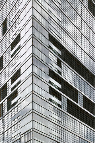 Modern glass office skyscraper corner with reflective windows and geometric facade in contemporary urban architecture
