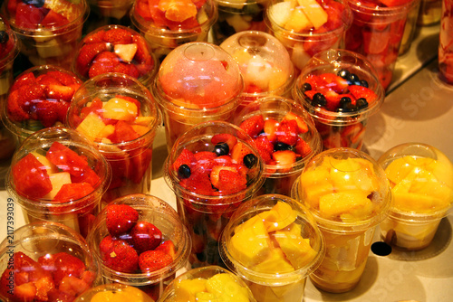 Fresh assorted fruit cups with strawberries blueberries pineapple melon and mixed seasonal fruit in takeaway containers