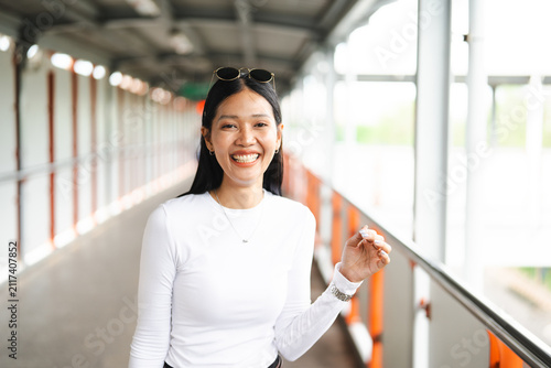 Photography Happy and cheerful portrait of a young Thai woman smiling on a pedestrian skywalk bridge in Bangkok