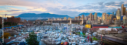 Granville Island marina in False Creek with Burrard Street Bridge and downtown skyline against mountains at sunset, Vancouver, British Columbia, Canada.