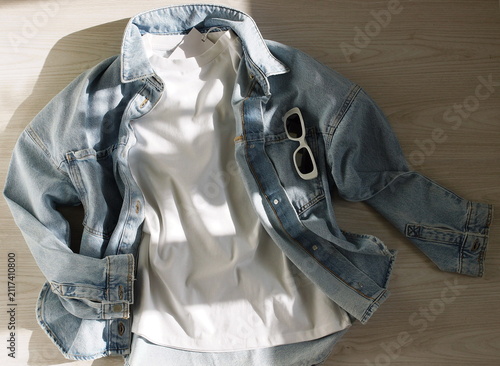 White T-shirt with label mock up , denim jacket, sunglasses flat lay top view fashion background. copy space. Mockup t-shirt casual outfit. Template blank shirt.