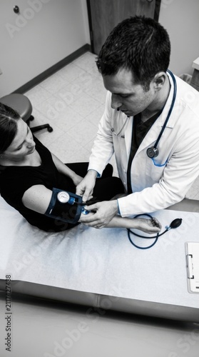 Doctor Checking Female Patient Blood Pressure During Medical Examination
