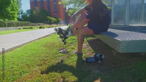 A skater prepares for adventure as they lace up their rollerblades on a sunny day, surrounded by vibrant greenery and a modern urban backdrop.