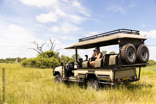 adult woman photographer leaning out of safari vehicle, Okavango Delta, Botswana, Africa