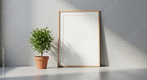 Empty wooden picture frame leaning on a wall next to a potted plant casting a shadow