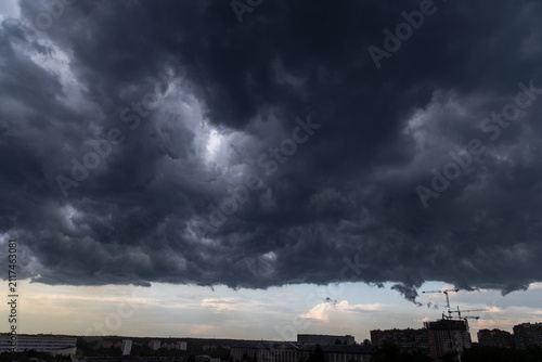 Impending storm clouds hovering over a distant city silhouette