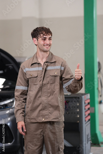 Mechanic car garage thumbs up uniform smiling man repair mechanic in garage giving thumbs up beside car, smiling with repair service confidence