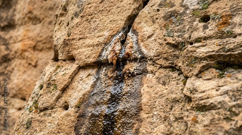 Natural Water Seepage Trickling Down a Weathered Sandstone Rock Face with Mineral Deposits and Ancient Geological Textures