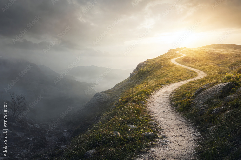 Fototapeta premium Winding path from foggy valley to sunlit hilltop