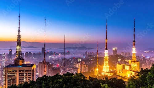 Modern Cityscape with Communication Towers at Twilight, Illuminated Buildings, and Foggy Valleys