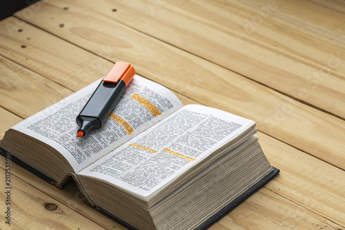 Canvas Print Open thick English dictionary book with orange highlighter marker pen resting on