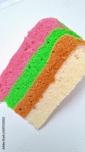 Close-up view of colorful layered steamed cake on a white background.