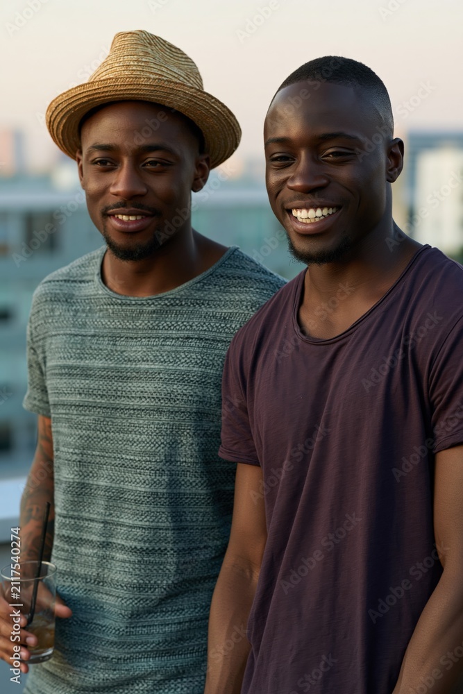 Obraz premium Two young men laughing on rooftop at sunset for city lifestyle portrait and casual urban background