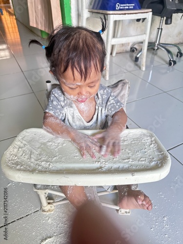 Messy Toddler Playing with White Powder in High Chair