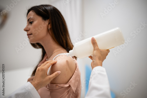 Foto Dermatologist applying topical treatment to patient's shoulder