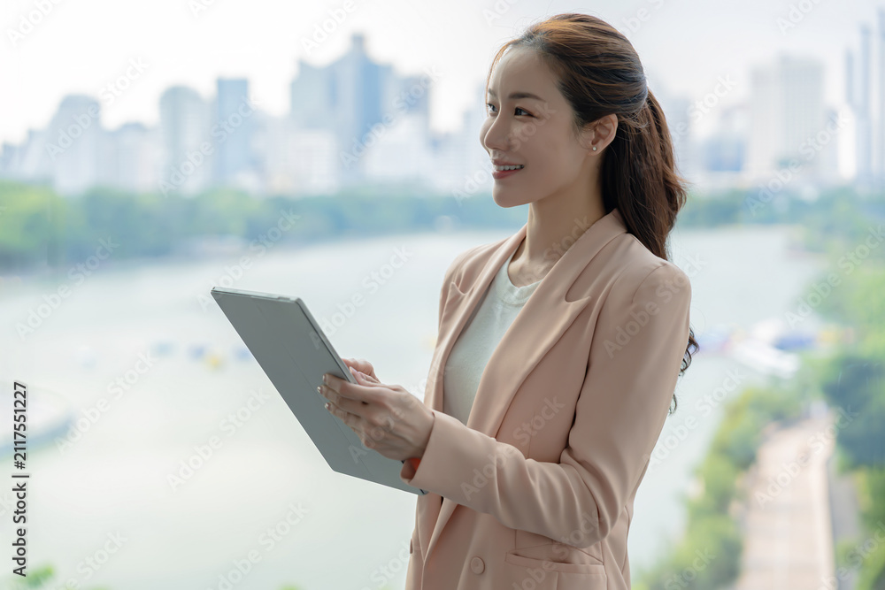Fototapeta premium Beautiful asian businesswoman using a digital tablet, representing a modern technology-driven workplace.