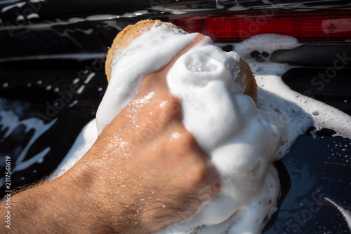 Foto Washing a car with soap and water near a driveway on a sunny day