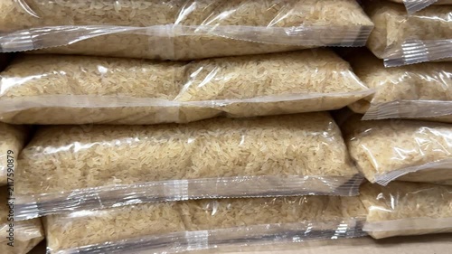 Neatly stacked rice packages create a well organized grocery display, offering shoppers a wide selection of staple food products for home cooking and commercial supply. Close up.