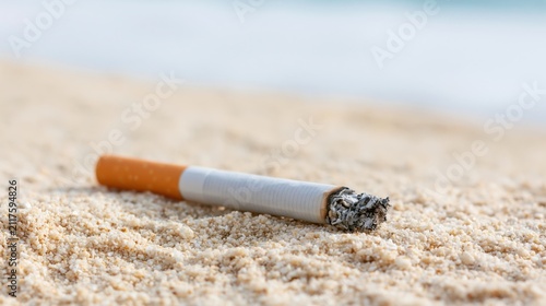The cigarette butt resting on a sunlit sandy beach with the ocean backdrop